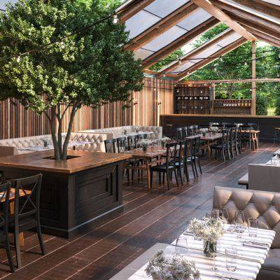 Restaurante con un salón de madera con un árbol y techo de cristal, muy luminoso.