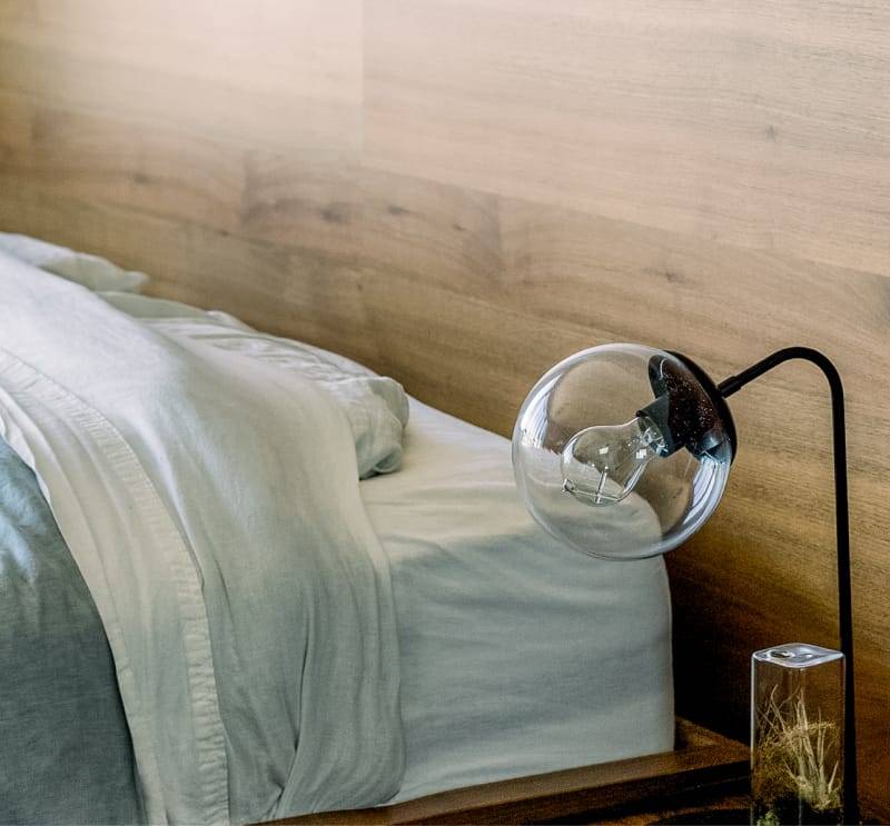 Cama con cabecera de madera y una lámpara