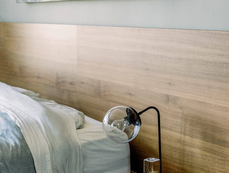 Estudio de interiorismo en Granada Dormitorio con cama de matrimonio, cabecera de madera y una lámpara de corte moderno.